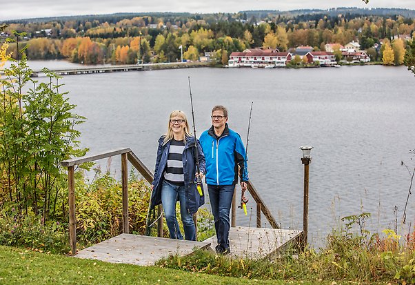 Bild på en man och en kvinna med fiskespö i händerna med indalsälven i bakgrunden