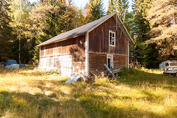 Fjäl 4:7. Byggnad i två våningar med liggande panel på undervåningen och stående på övervåningen. Grå dubbelport och fönster med spröjs.