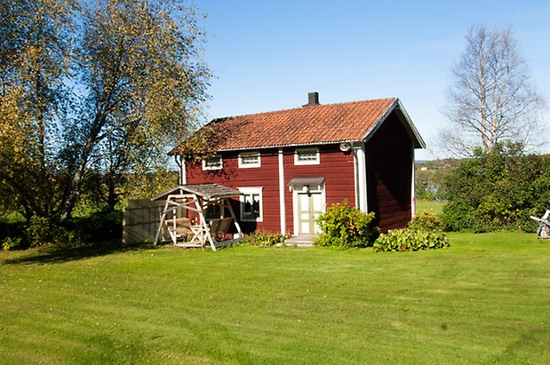 Fjäl 6:11. Timrat, rödmålat hus med vit/gröna dubbeldörrar med fönster med gröna spröjs.