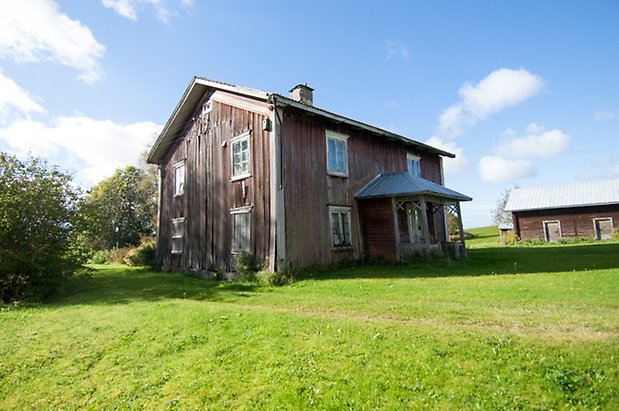 Husås 3:50. Hus i mörk panel med förstukvist och fönster med spröjs.