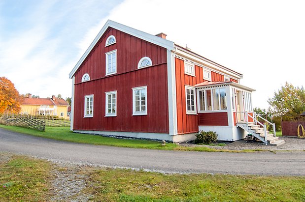 Hölje 2:6. Hus i tre våningar i röd panel med punschveranda och fönster med vita spröjs.