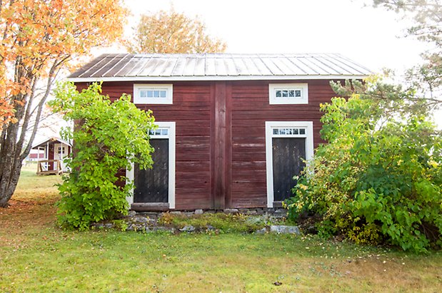 Hölje 3:4. Timrad, röd byggnad med två svarta dörrar och små fönster med spröjs. 