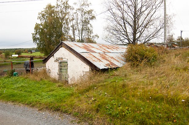 Klösta 2:4. Jordkällare med vit puts och grön dörr.