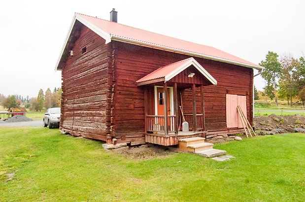 Klösta 4:12. Timrad, röd byggnad med förstukvist och gul dörr.