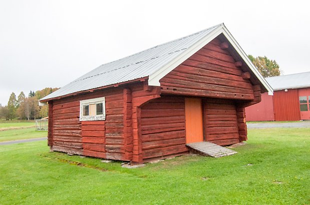 Klösta 4:12. Timrad, röd byggnad med gul lucka. 