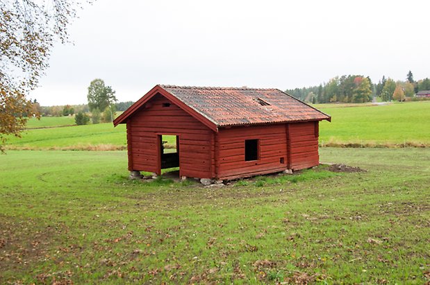 Klösta 4:12. Röd, timrad byggnad på äng.