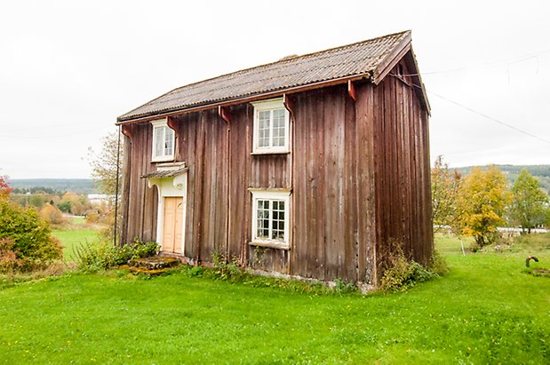 Korsta 1:19. Hus i två våningar med gula dubbeldörrar och fönster med vita spröjs. 