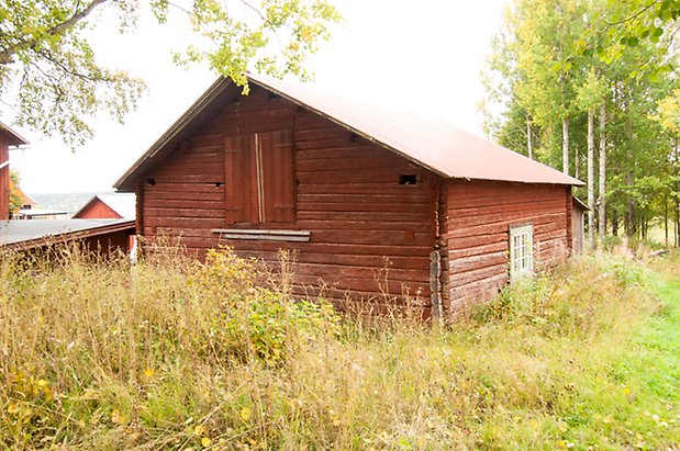 Korsta 1:19. Timrad, röd byggnad med lucka och fönster med vita spröjs.