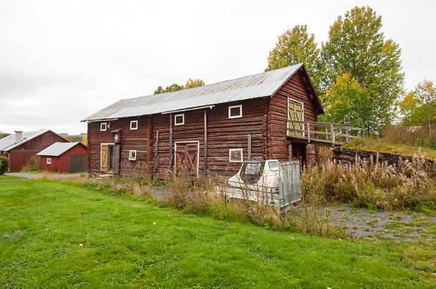 Korsta 1:19. Timrad ladugård med en grön dubbelport, en gul dubbelport och en röd dubelport.