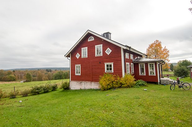 Korsta 2:12. Rött, timrat hus med punschveranda och fönster med vita spröjs. 