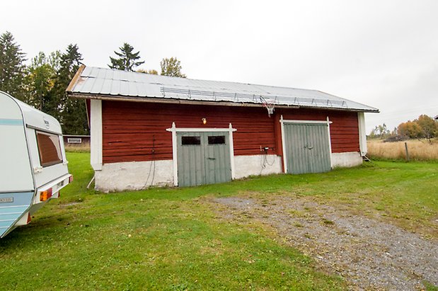 Korsta 2:12. Timrad byggnad med två blå garageportar.