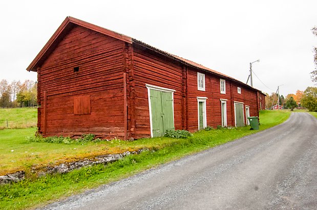 Korsta 2:17. Timrad, röd ladugård med två gröna dubbelportar och tre gröna portar, fönster med vita spröjs.