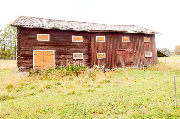 Korsta 2:19. Ladugård i panel och timmer, en gul dubbelport och en röd dubbelport och gula luckor. 