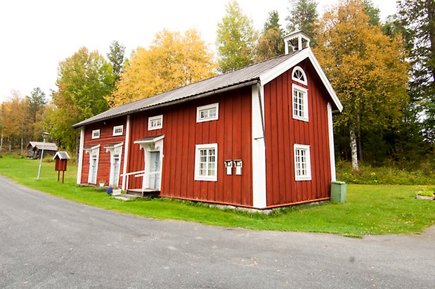 Lits Prästbord 1:18. Rött hus i panel och timmer, tre grå dörrar, fönster med vita spröjs, liten klockstapel på taket.