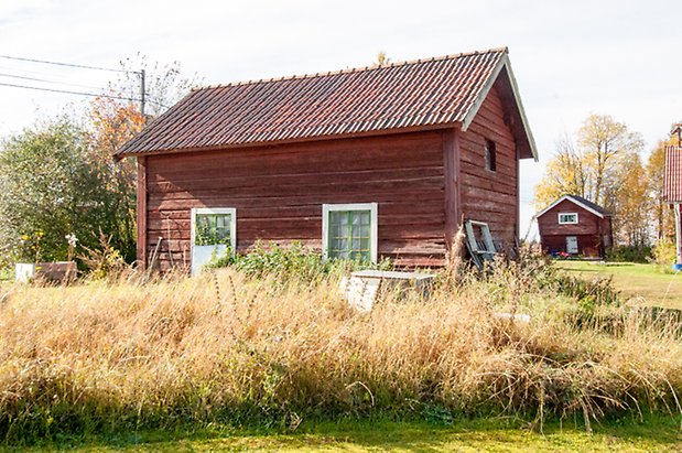 Mo 4:26. Timrad byggnad i två våningar med fönster med gröna spröjs.