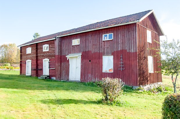 Palleråsen 1:4. Byggnad i röd panel och timmer, vi dubbeldörr och två vita portar.