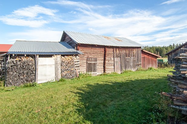 Palleråsen 1:8. Byggnad i grånad panel och timmer.