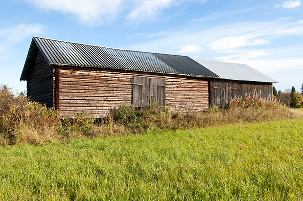 Palleråsen 1:8. Grå byggnad i timmer och panel.