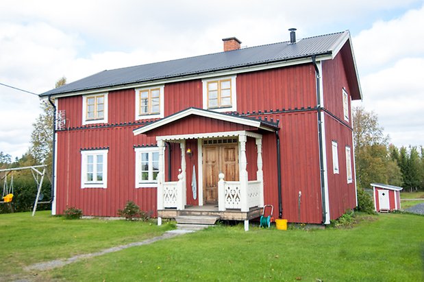 Ringsta 2:14. Hus i två våningar i röd panel med förstukvist med snickarglädje. Fönster med gula spröjs.