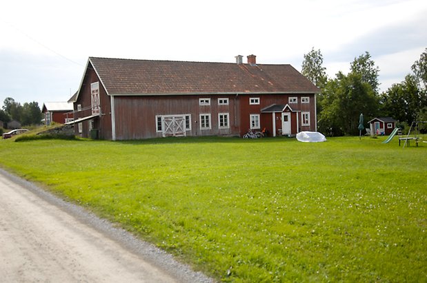 Bräcke 2:6. Ladugård i två våningar i brun panel med fönster med vita spröjs, två dubbeldörrar och vit dörr.