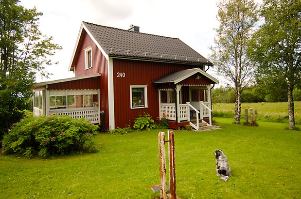 Måläng 1:10. Hus i två våningar i röd panel med förstukvist och inglasad veranda.