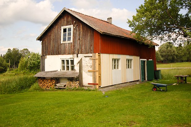 Måläng 1:10. Ladugård i två våningar med vit panel på undervåningen och röd och brun panel på övervåningen. Grön dubbelport och fönster med vita spröjs.