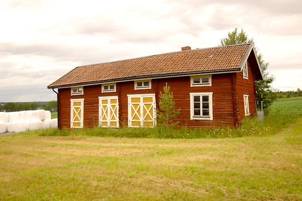 Orrviken 2:18. Timrad, röd byggnad med två gul, vita dubbelportar och en port, fönster med vita spröjs.