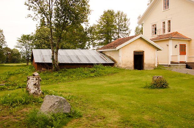 Sunne Prästbord 1:13. Timrad, låg byggnad, byggnad i ljusgul puts och gaveln på ett hus i ljusgul, liggande panel.