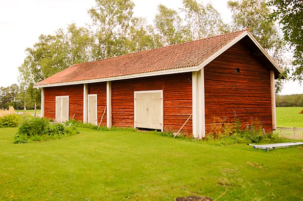 Sunne Prästbord 1:13. Röd, timrad byggnad med gul dubbelport och tre gula portar.