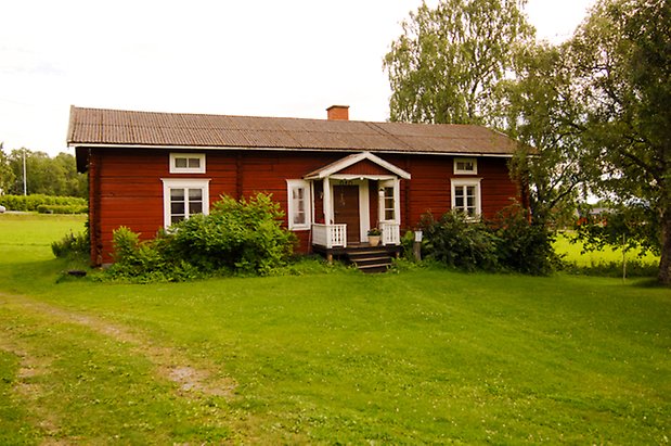 Sunne-Gärde 4:1. Timrad, röd stuga i två våningar och förstukvist, med fönster med vita spröjs.