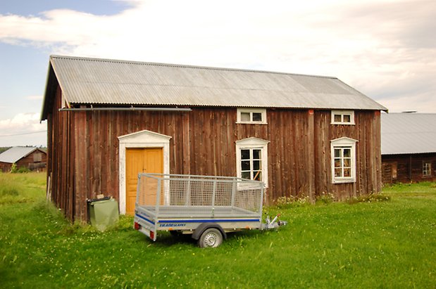 Sunne-Svedje 1:3. Byggnad i brun panel med gul dubbeldörr och fönster med vita spröjs.