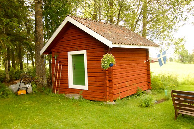 Åkeräng 1:13. Timrad byggnad med grön lucka.