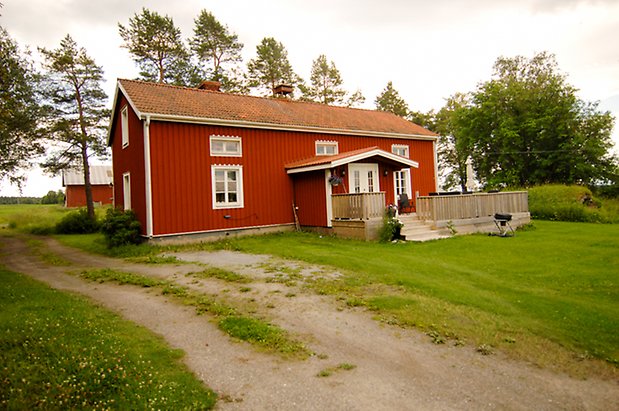 Åkeräng 1:16. Hus i två våningar i röd panel med vita dubbeldörrar och fönster med vita spröjs.