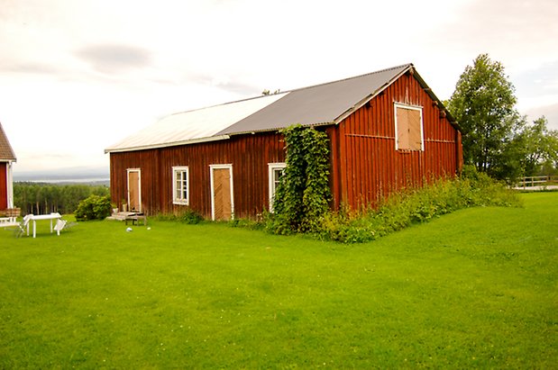 Åkeräng 1:16. Byggnad i två våningar i röd panel med två gula portar, med gul lucka på övervåningen. Fönster med vita spröjs.