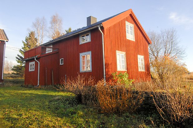 Bjärme 3:1. Hus i två våningar i röd panel med fönster med spröjs.