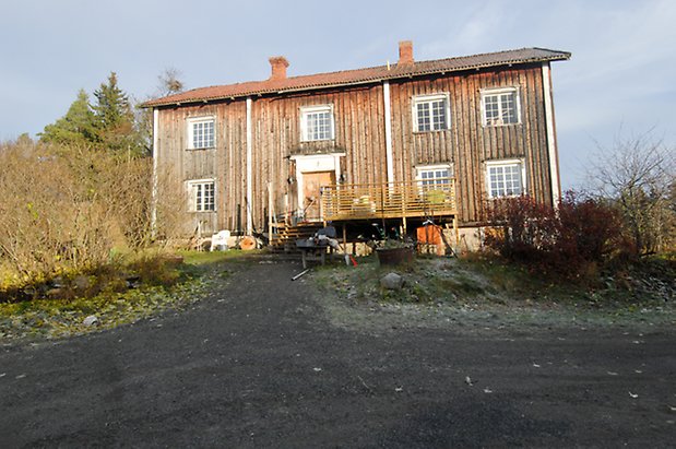 Klocksåsen 1:2. Hus i två våningar i grå panel med gul dubbelport och fönster med vita spröjs. 