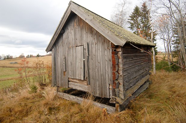 Kungsnäset 1:35. Byggnad i grått timmer och panel med lucka.