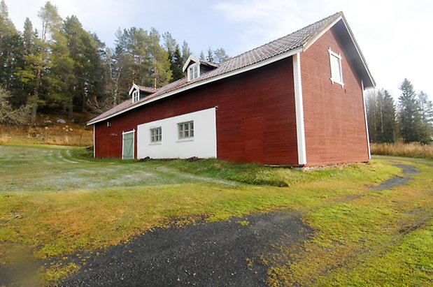 Åsan 1:9. Ladugård i två våningar, i röd, liggande panel och vit puts. Grön dubbelport och fönster med gröna spröjs och två takkupor.