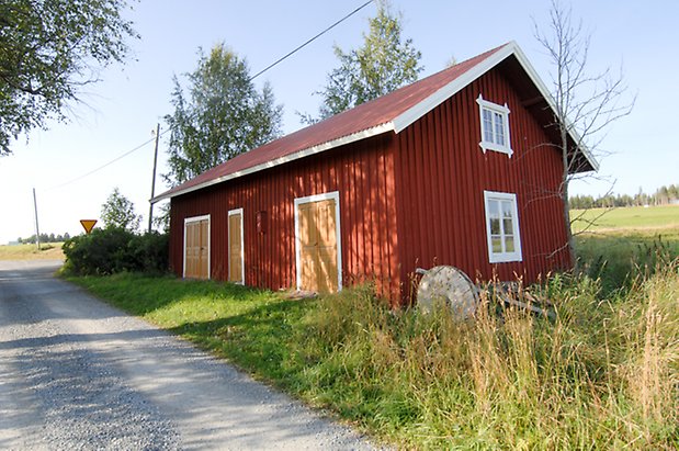 Jälsta 1:2. Byggnad i röd panel i två våningar med två dubbelportar i gul och en port i gult, fönster med vita spröjs.