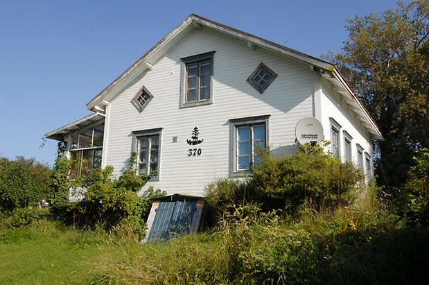 Norderöns-Ålsta 1:4. Villa i vit liggande panel med grå detaljer, inglasad veranda och fönster med grå spröjs.