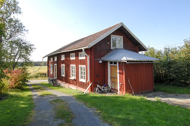 Norderöns-Ålsta 1:23. Byggnad i röd panel i två våningar med fönster med vita spröjs och gula portar.