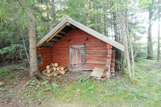 Trusta 2:5. Byggnad i rött timmer med lucka.