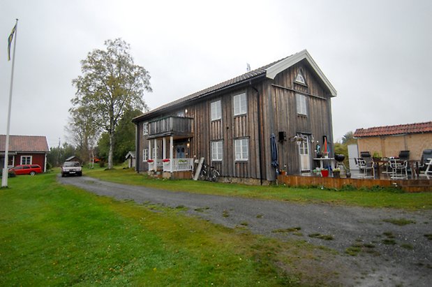 Västanede 1:6. Hus i grå panel i två våningar, förstukvist med balkong ovanför, fönster med vita spröjs.