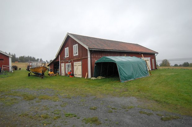 Västanede 1:6. Ladugård i röd panel med två gula dubbelport och en port och fönster med vita spröjs. 