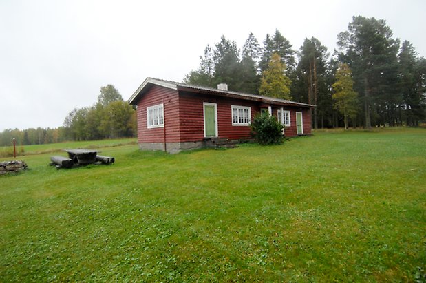 Västanede 2:2. Litet hus i liggande, röd panel två gröna dörrar och fönster med vita spröjs.