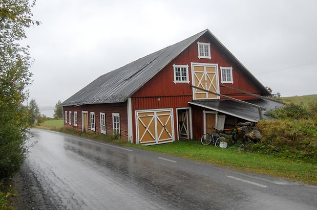 Västanede 3:5. Ladugård i två våningar med rött timmer och panel, två gul/vita dubbelport, en gul port, fönster med vita spröjs.