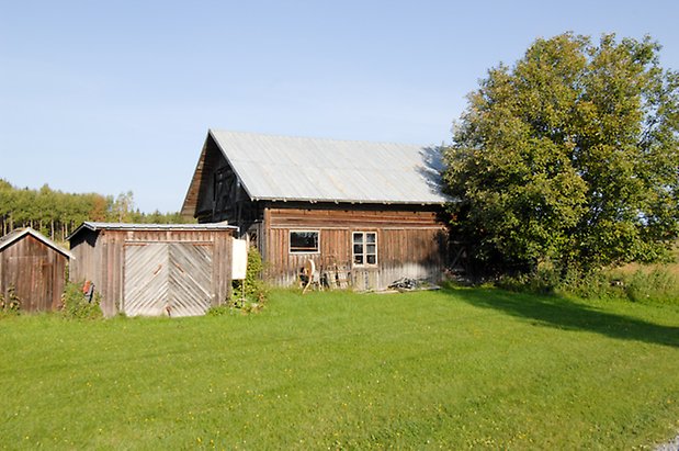 Önsta 2:18. Byggnad i brun panel med fönster med spröjs, bredvid en byggnad i brun panel med garageport.