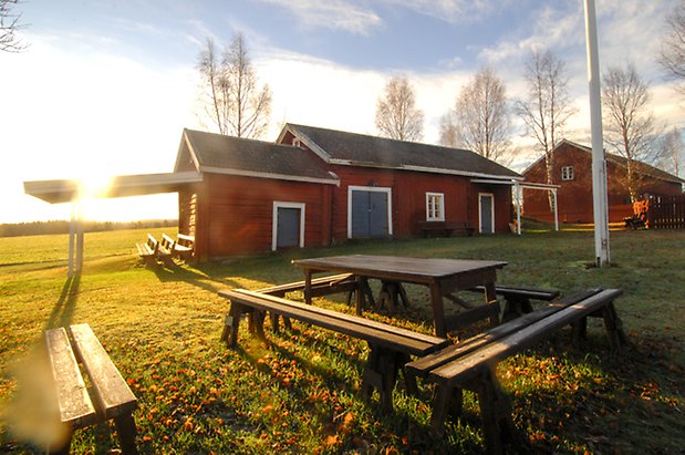 Marieby Prästbord 1:4. Byggnad i rött timmer med en blå dubbelport och två blå portar.