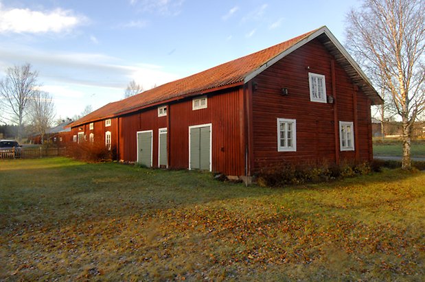 Marieby-Bye 4:29. Ladugård i två våningar i röd panel med tre grå dubbelportar och en port och fönster med vita spröjs.