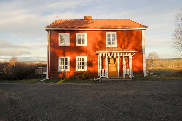 Öd 1:11. Hus i två våningar i röd panel, förstukvist, gul dubbeldörr, fönster med vita spröjs.